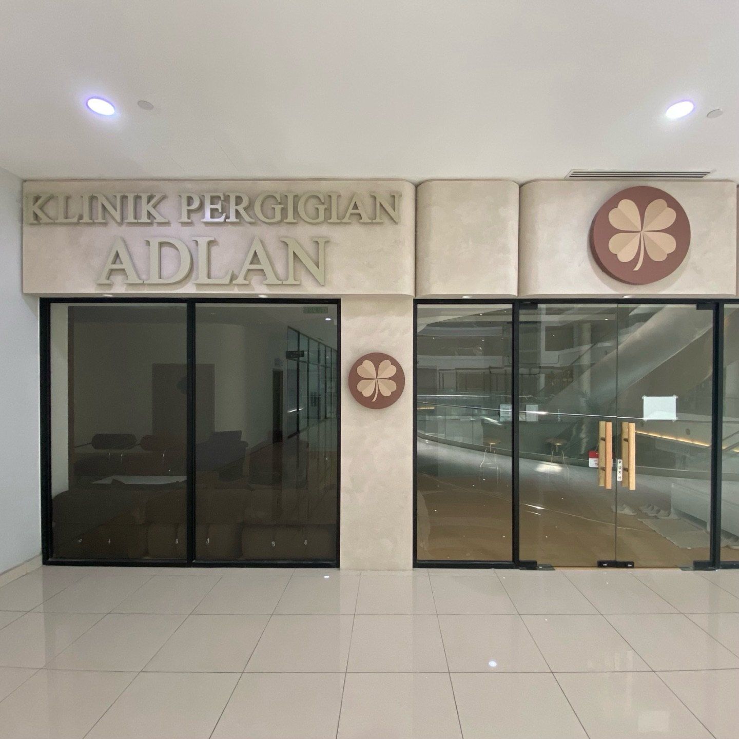 ADLAN Dental clinic shopfront in Bangi, a pale textured wall with the clinic name and two glass doors