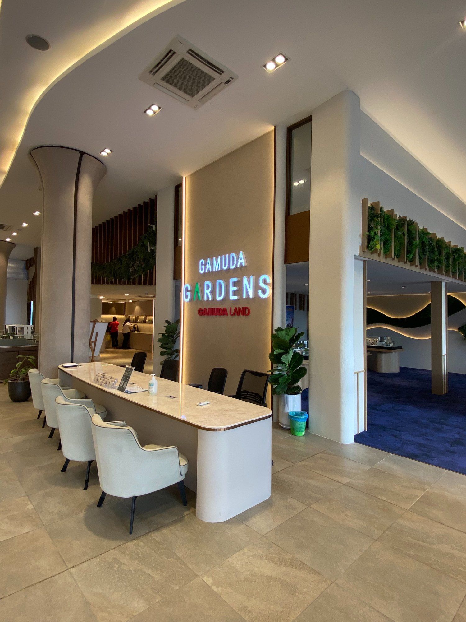 A property sales gallery with a long white reception counter and textured feature walls