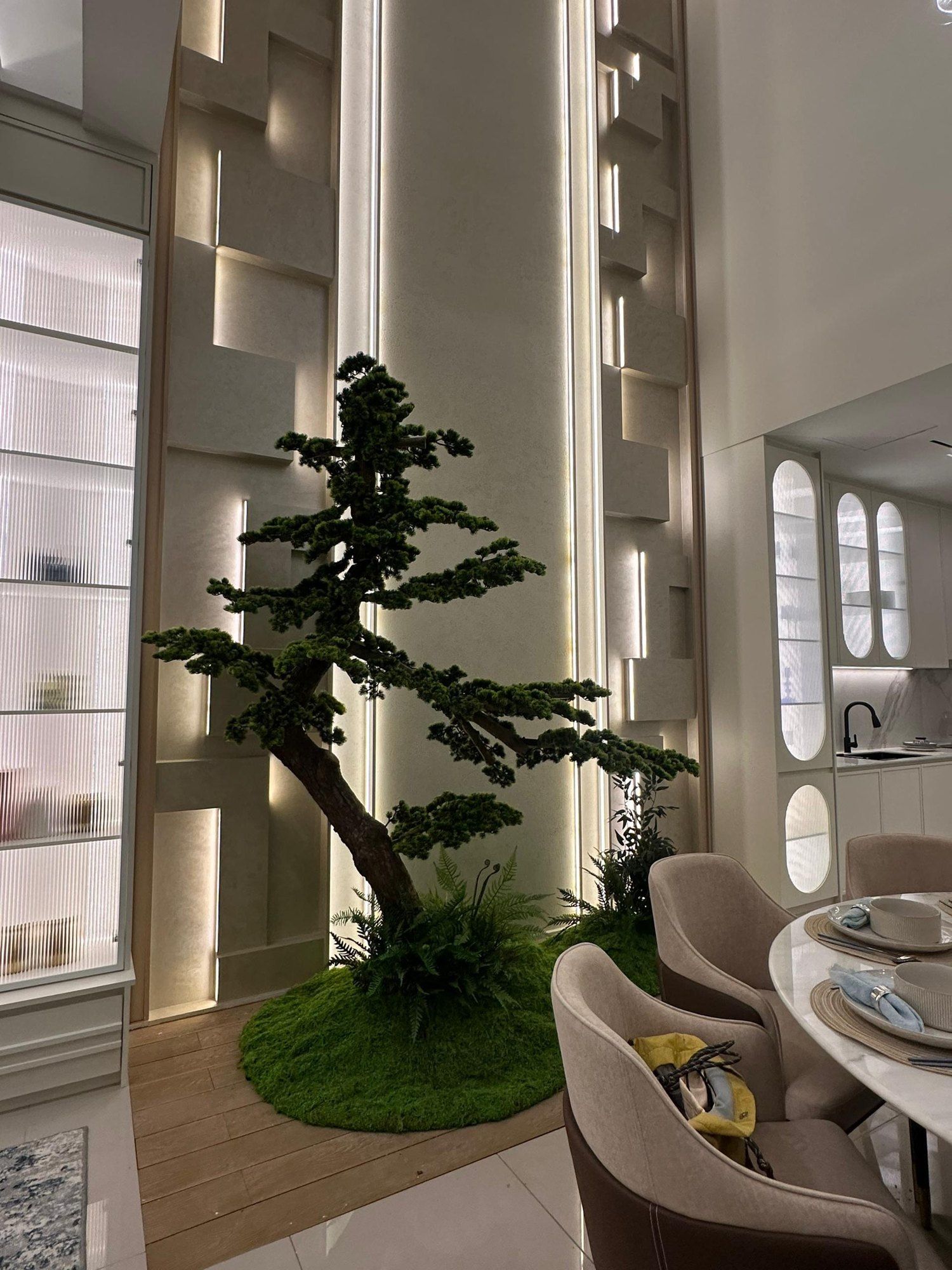 A mock-up unit dining corner with a bonsai, curved shelves and pale textured walls